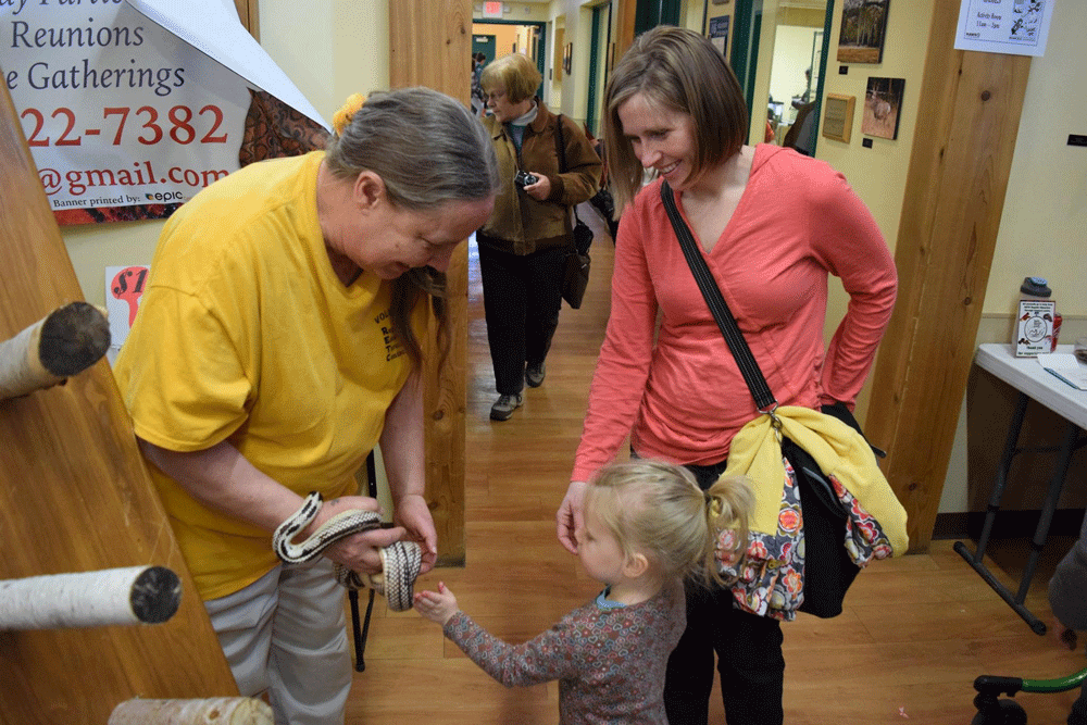 Woman holding a snake in front of a girl.